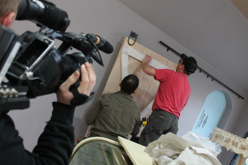 Andy and Matthias install the barn door that Andy made to separate the showroom from the prep room.