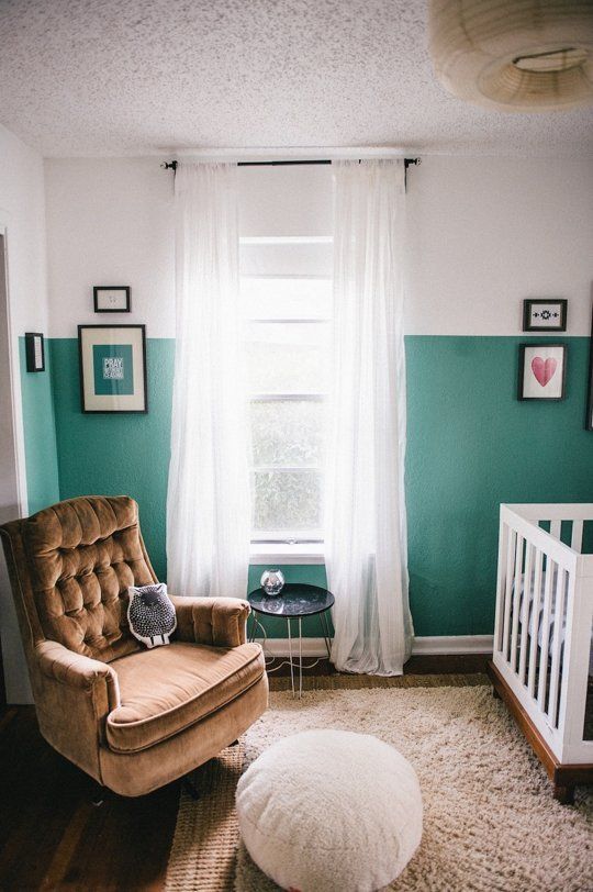 This little nursery proves that you don't have to splurge to get a charming little room. A comfortable chair with a fun little pouf sits cozily next to a simple crib. The bold green color on the lower 2/3 of the wall help give the room extra height, as the bright white ceiling feels like it is even taller as the color cascades down the walls.