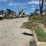 Fort Washington Tornado 6 Why I Joined a Tornado Clean Up Chainsaw Gang MyFixitUpLife Suburban street littered with fallen branches and debris after a storm utility bucket trucks and crews repairing power lines in the distance quintessential scene of storm recovery MyFixitUpLife