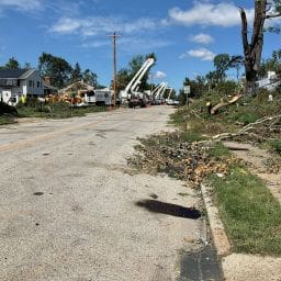 Fort Washington Tornado 6 Why I Joined a Tornado Clean Up Chainsaw Gang MyFixitUpLife Suburban street littered with fallen branches and debris after a storm utility bucket trucks and crews repairing power lines in the distance quintessential scene of storm recovery MyFixitUpLife
