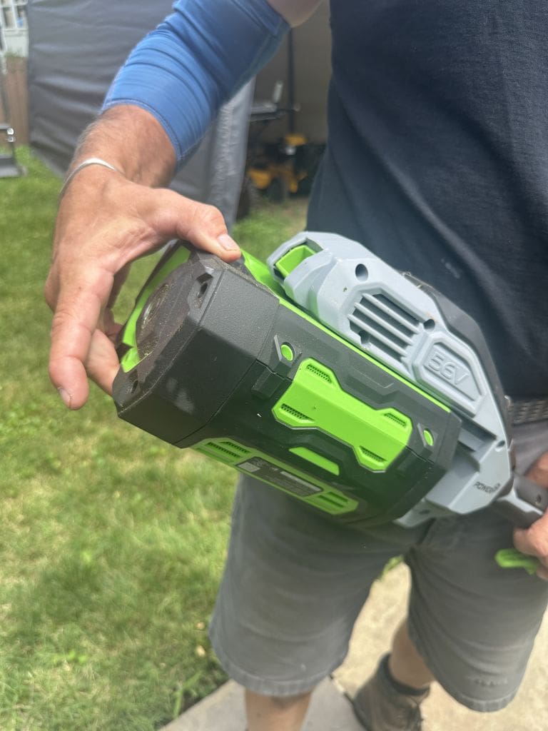 EGO String Trimmer battery Should You Try an eGo String Trimmer Maybe not MyFixitUpLife MyFixitUpLife Person holding a green and black cordless power tool with a bulky gray battery pack outdoors MyFixitUpLife